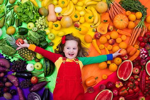 Child laying in vegetables and fruits