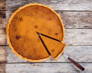 A pumpkin pie with a a slice being taken out.
